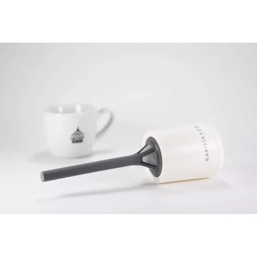Passoire en plastique blanc pour thé et café avec une tasse en arrière-plan.