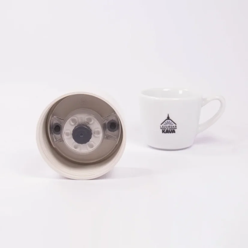 Detail of the lid of a ceramic thermos from the underside with coffee in the background.