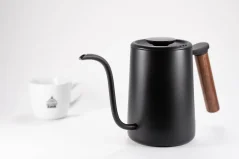 Black rapid-boil kettle with a wooden handle by Timemore Fish Youth on a white background, accompanied by a cup with coffee motifs.