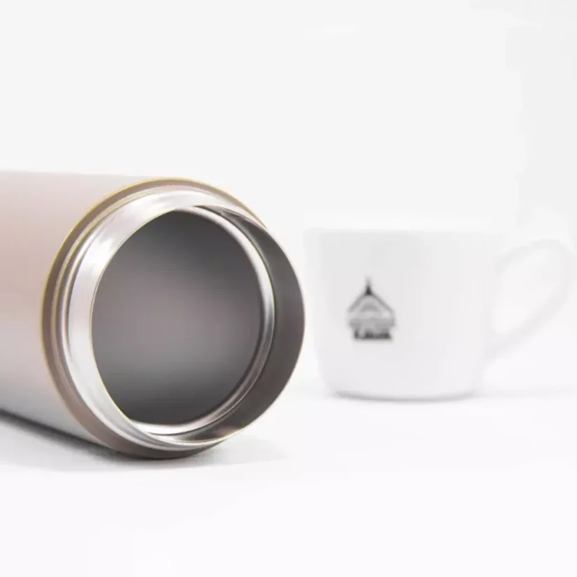 Preview of the Kino Travel Tumbler Khaki 500ml thermos with a cup of coffee in the background