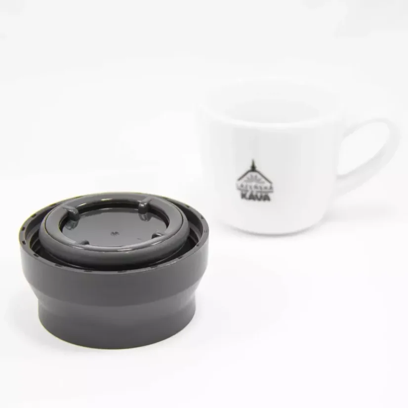 View of a part of the lid of the Kino Travel Tumbler Coyote 500ml thermos, with a cup of coffee in the background.