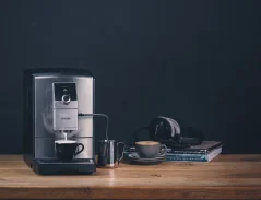 Sudraba krāsas Nivona 799 kafijas automāts ar kapučīno pagatavošanas funkciju, novietots uz galda.