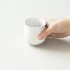 Biały kubek do kawy z filtrem Origami Pinot Flavor w dłoni.