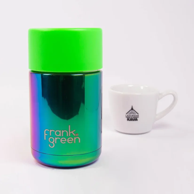 Ceramic thermal mug with coffee in the background.