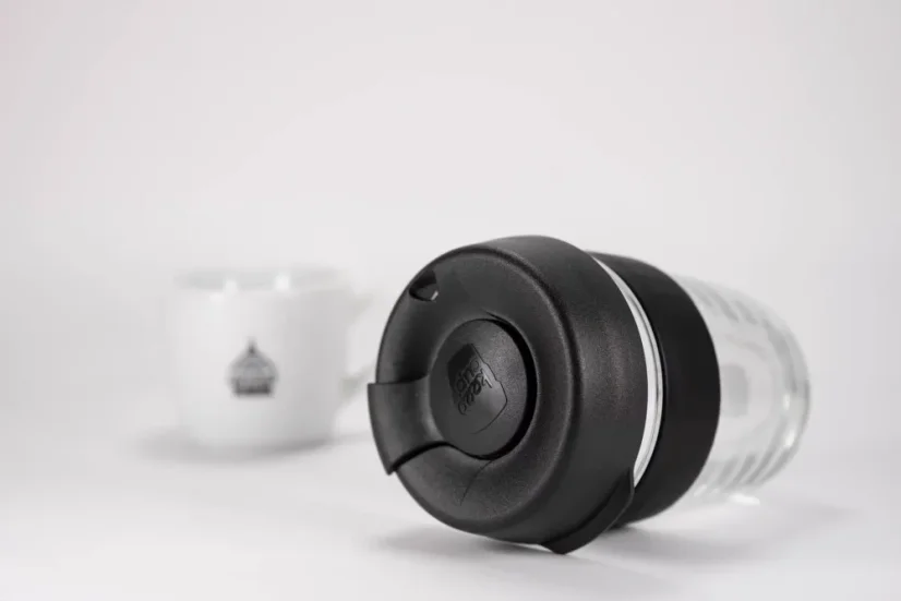 Gobelet thermique en verre avec un couvercle noir et une poignée en caoutchouc noir, d'une capacité de 340 ml, détail sur le couvercle.