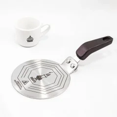 Close-up of a Bialetti induction plate on a white table, accompanied by a porcelain cup with coffee motifs. Close-up of a Bialetti induction plate on a white table, accompanied by a porcelain cup with coffee motifs.
