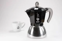 Cafetière moka en aluminium compatible induction avec le logo du fabricant - la société italienne Bialetti, accompagnée d'une tasse avec un logo. Cafetière moka en aluminium compatible induction avec le logo du fabricant - la société italienne Bialetti, accompagnée d'une tasse avec un logo.