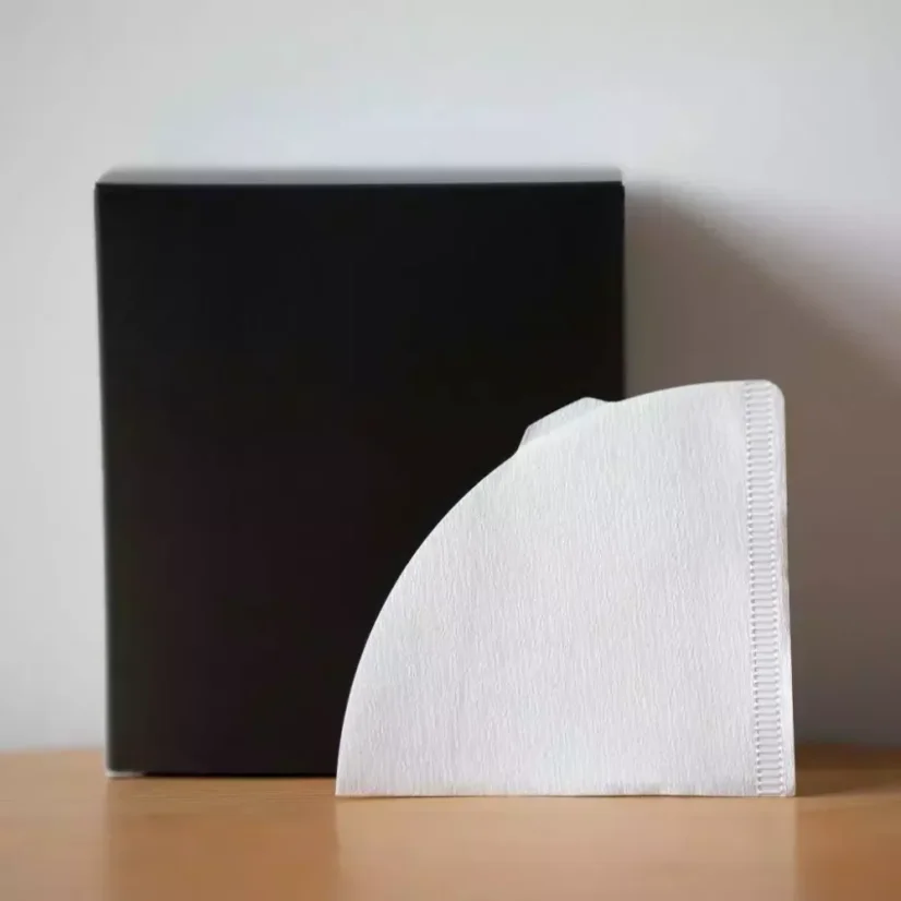 Filtres en papier blancs pour V60 avec une boîte noire en arrière-plan.