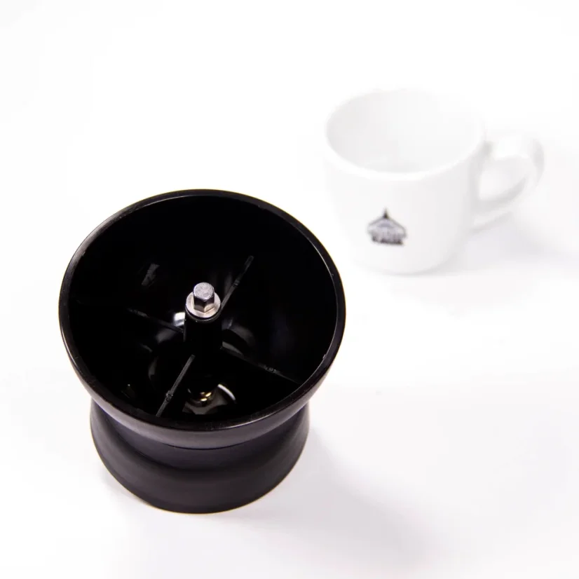 Detailansicht des Einfülltrichters der manuellen Kaffeemühle Hario Skerton Pro auf weißem Hintergrund mit einer Tasse Kaffee.