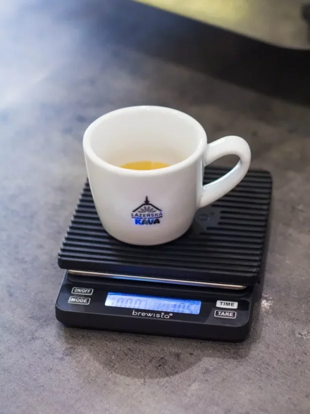 Balance numérique allumée avec un tapis en caoutchouc et une tasse à espresso