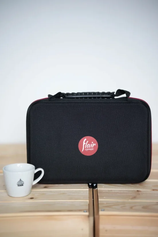 Black bag for the Flair Pro 2 espresso machine on a wooden table with a cup of coffee.