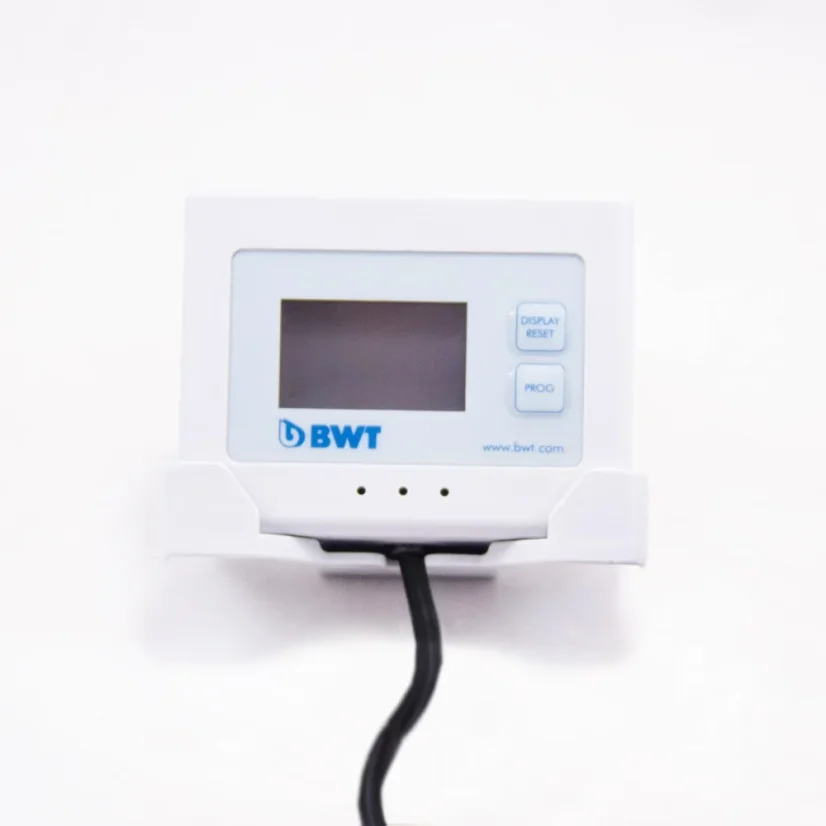 LCD-Display der Marke BMWT AQA zur Wasserfiltration mit schwarzem Kabel auf einem weißen Tisch zusammen mit einer Tasse auf weißem Hintergrund.