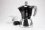 Cafetière moka en aluminium convenant à l'induction avec le logo du fabricant, la société italienne Bialetti, accompagnée d'une tasse comportant un fruit à baies.