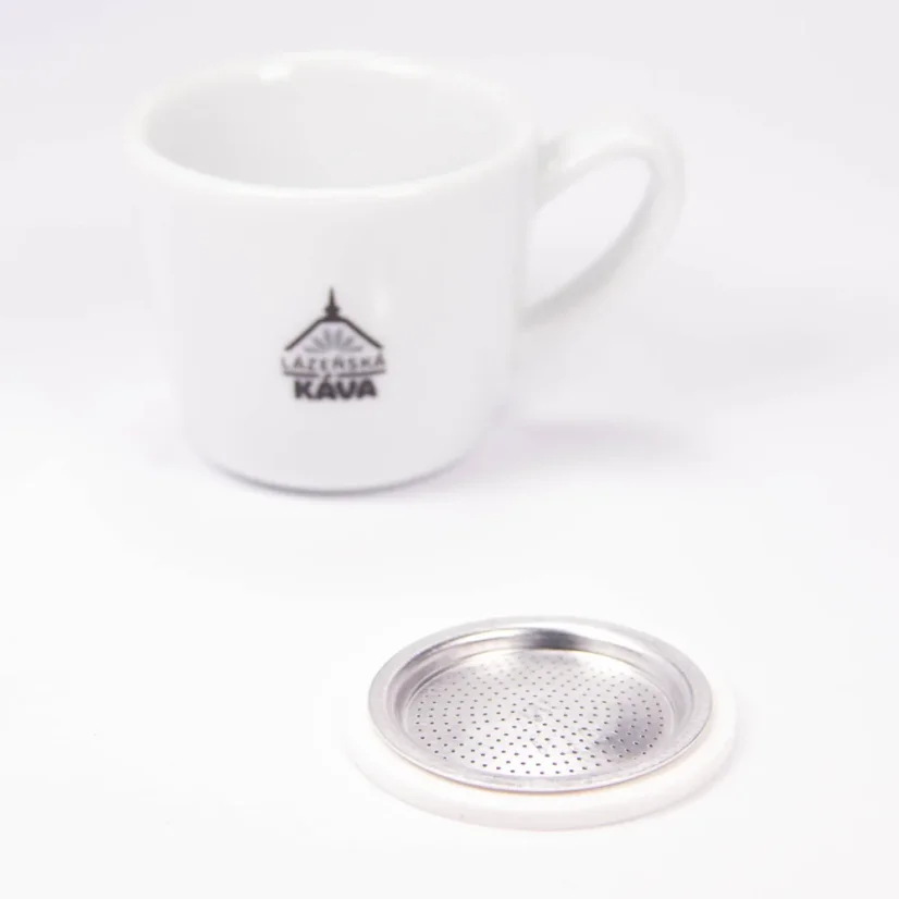 Guarnizione e filtro di ricambio Bialetti accanto a una tazza di caffè con logo.