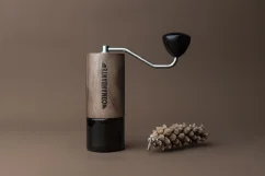 Manual Comandante grinder in Virginia Walnut color on a brown background.