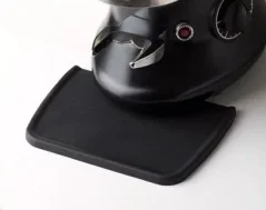 Czarna podkładka pod tamper, idealna do ochrony blatu kuchennego podczas tampowania kawy.