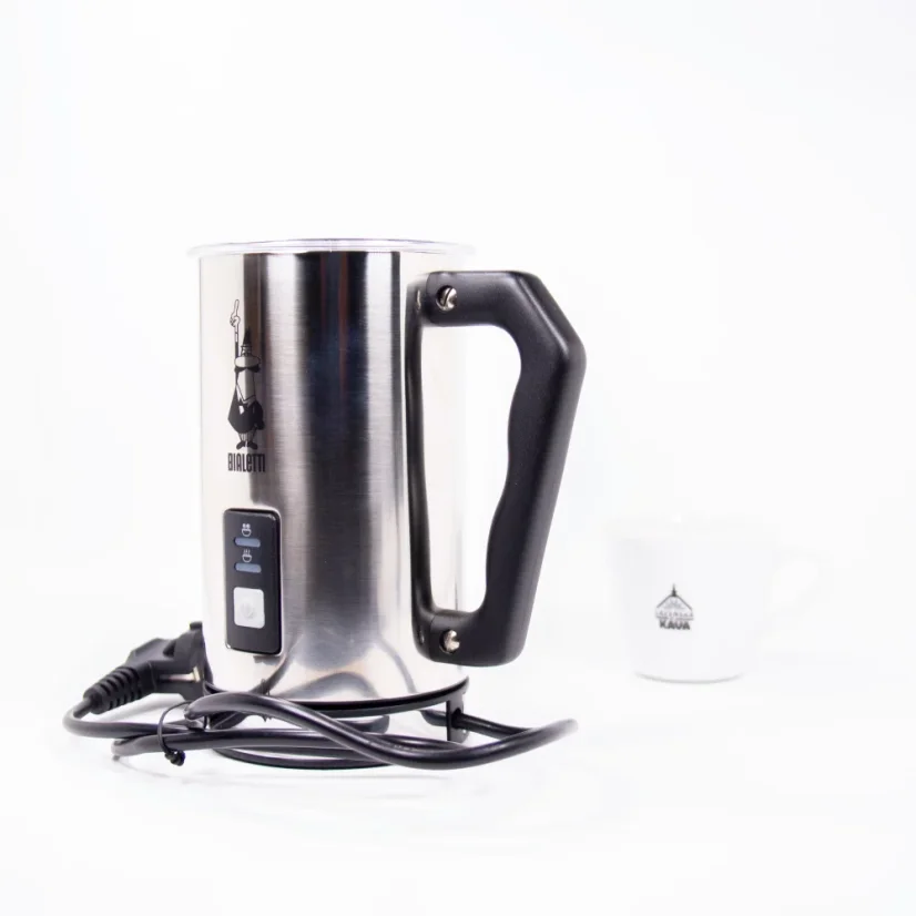The image shows a coffee cup and an electric milk frother by Bialetti. The frother is made of stainless steel with a black handle, lid, and base.