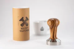Stainless steel 53 mm Heavy Tamper Zebrano with a cup of coffee