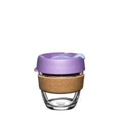 Glass coffee mug with a purple lid and cork holder.