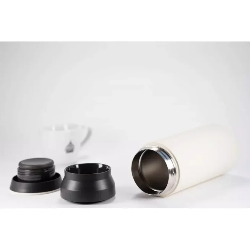 Bouteille isotherme blanche en acier inoxydable de 500 ml, présentée avec le couvercle ouvert, sur un fond blanc avec une tasse de café.