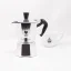 Silver Bialetti Moka Express pot for 2 cups on a white background with a cup of coffee