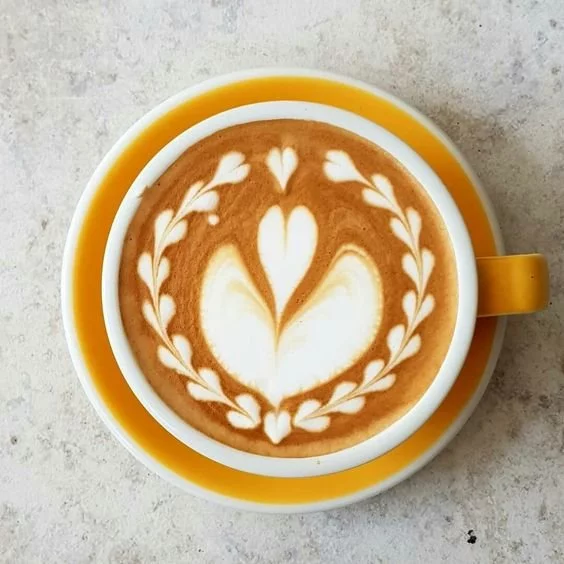 Détail de latte art dans une tasse jaune.