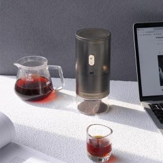 Timemore Go grinder together with a server and a glass of coffee.