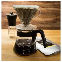 Plastic dripper, glass jar with handle, coffee grinder, coffee packaging on a rustic background Plastic dripper, glass jar with handle, coffee grinder, coffee packaging on a rustic background
