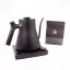 Black electric kettle on a black stand with a white background and a package of coffee, detail on the kettle handle