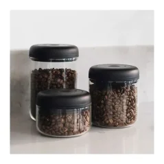 Bocaux en verre de différentes tailles avec un couvercle noir et des grains de café à l'intérieur