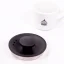 Détail du couvercle d'une bouilloire électrique noire sur un fond blanc avec une tasse de café