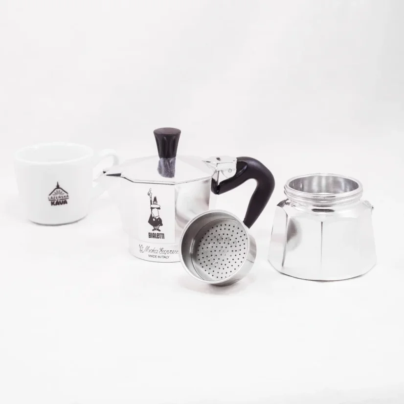 Disassembled parts of a silver Bialetti Moka Express pot on a white background with a cup of coffee.
