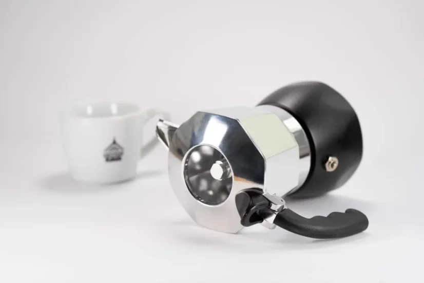 Bialetti Brika moka pot for 2 cups placed in the background with a cup of coffee.