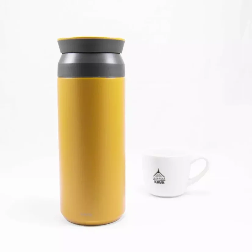 Yellow Kinto Travel Tumbler Coyote 500ml thermos on a background with a cup of coffee.