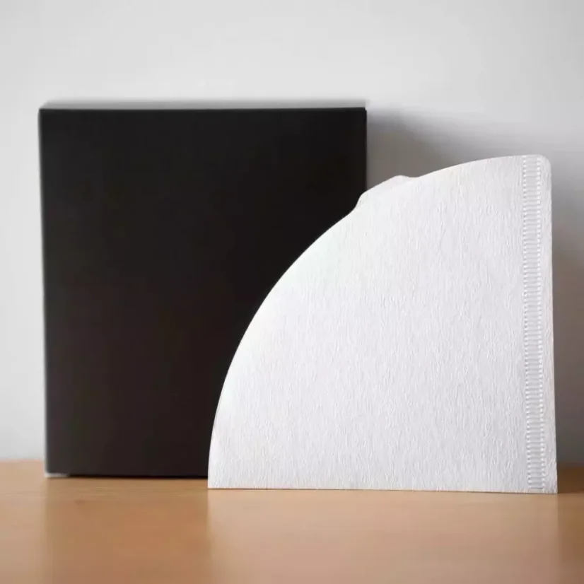 Weißer Papierfilter auf einem Holztisch, schwarze Box und weißer Hintergrund