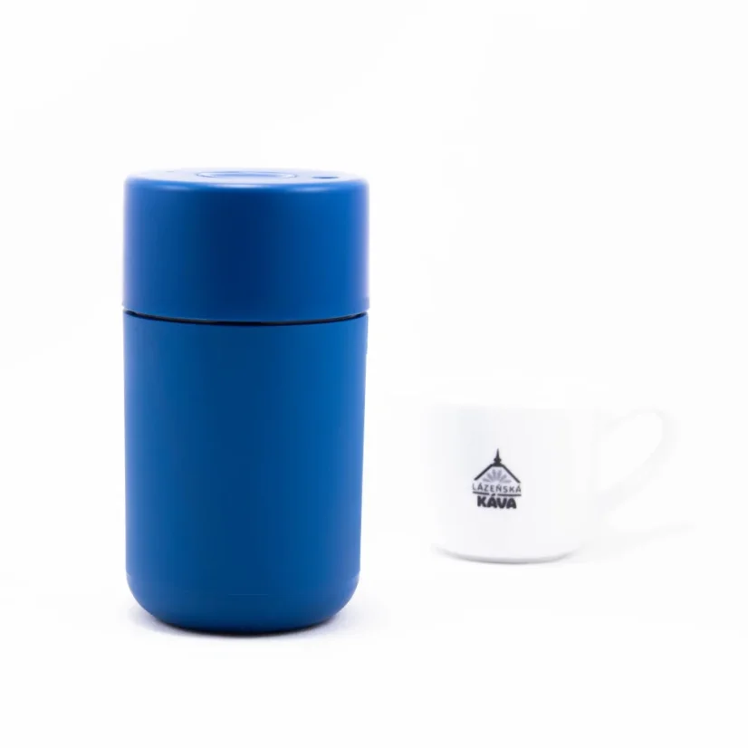 Plastic thermal mug from the back with coffee in the background.