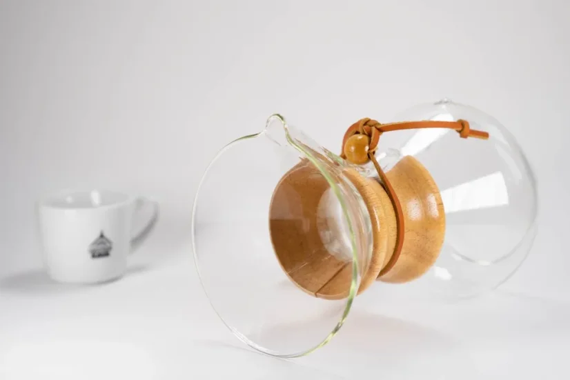 Chemex en verre avec poignée en bois et lanière en cuir, tasse blanche avec logo pour le café.