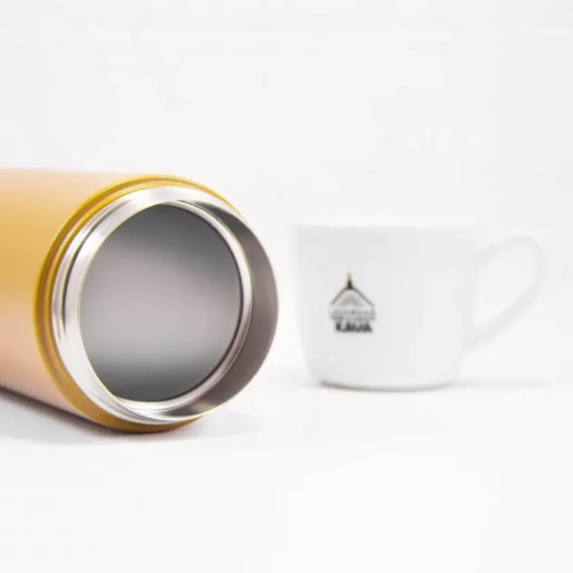 Detail of the edge of a yellow Kinto TravelTumbler Coyote 500ml thermos with a coffee cup in the background.
