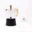 Silver moka pot with a wooden handle, Forever Miss Moka Woody, designed for 3 servings of coffee with a porcelain cup in the background.