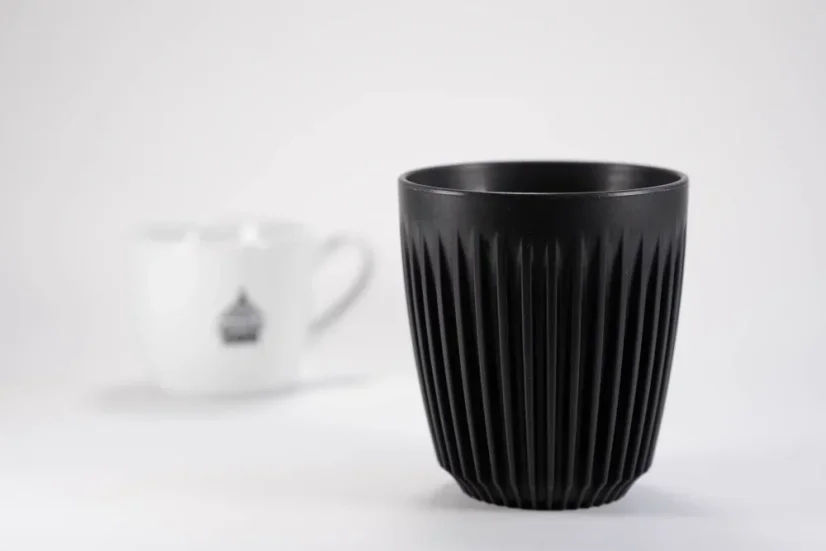 Čierny ekologický termohrnček bez viečka s objemom 240 ml na bielem pozadí s šálkou kávy.