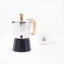 Moka pot with a wooden handle and black water spout for two servings of coffee, Forever Miss Moka Woody with a white cup in the background