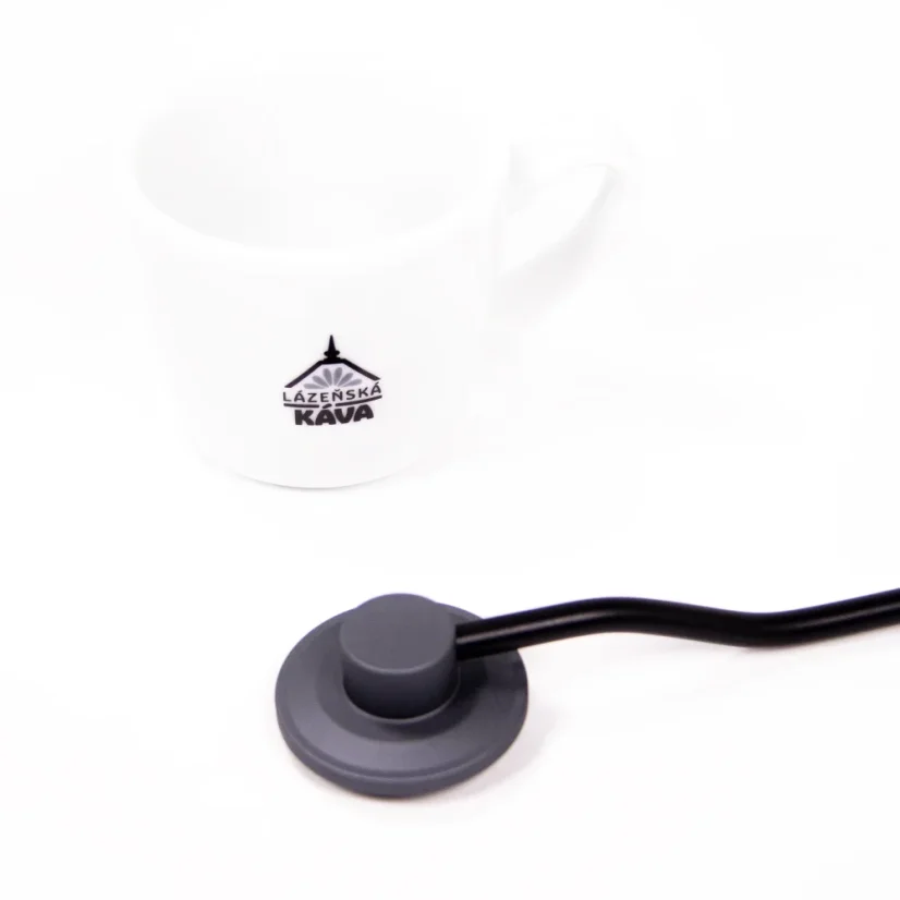 Detail of the handle of a Timemore manual coffee grinder on a white background with a cup of coffee