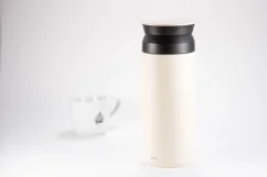Nerezová biela termofľaša o objeme 500 ml na bielom pozadí so šálkou kávy.