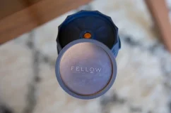 Fellow Prismo pour Aeropress en couleur noire avec un couvercle sur une table en verre.