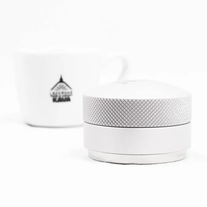ECM Tamper with coffee in the background.