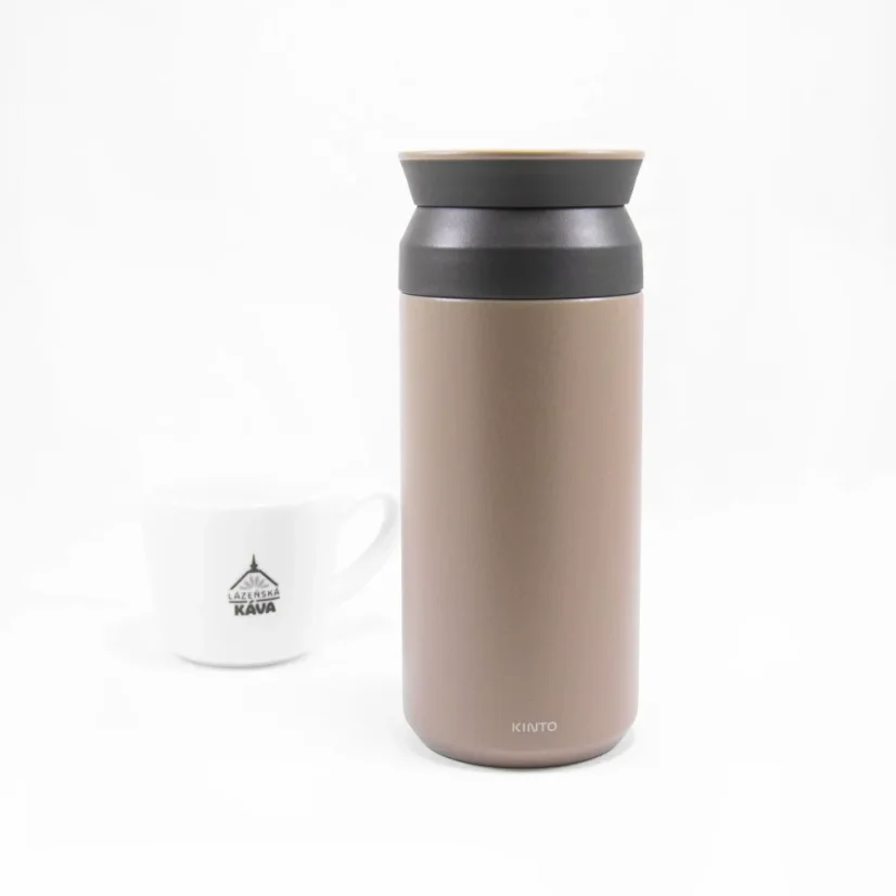 Khaki-colored Kinto Travel Tumbler 350ml on a white table with a cup of coffee.