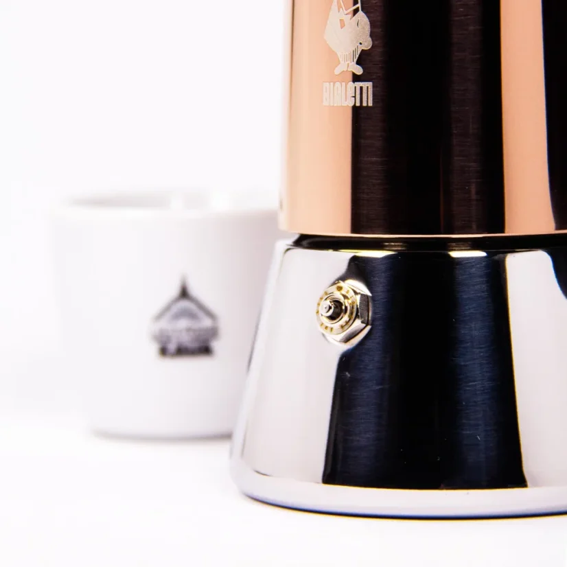 Cafetera Moka Bialetti New Venus para 4 tazas sobre un fondo blanco con una taza de café, vista del pistón de la cafetera Moka