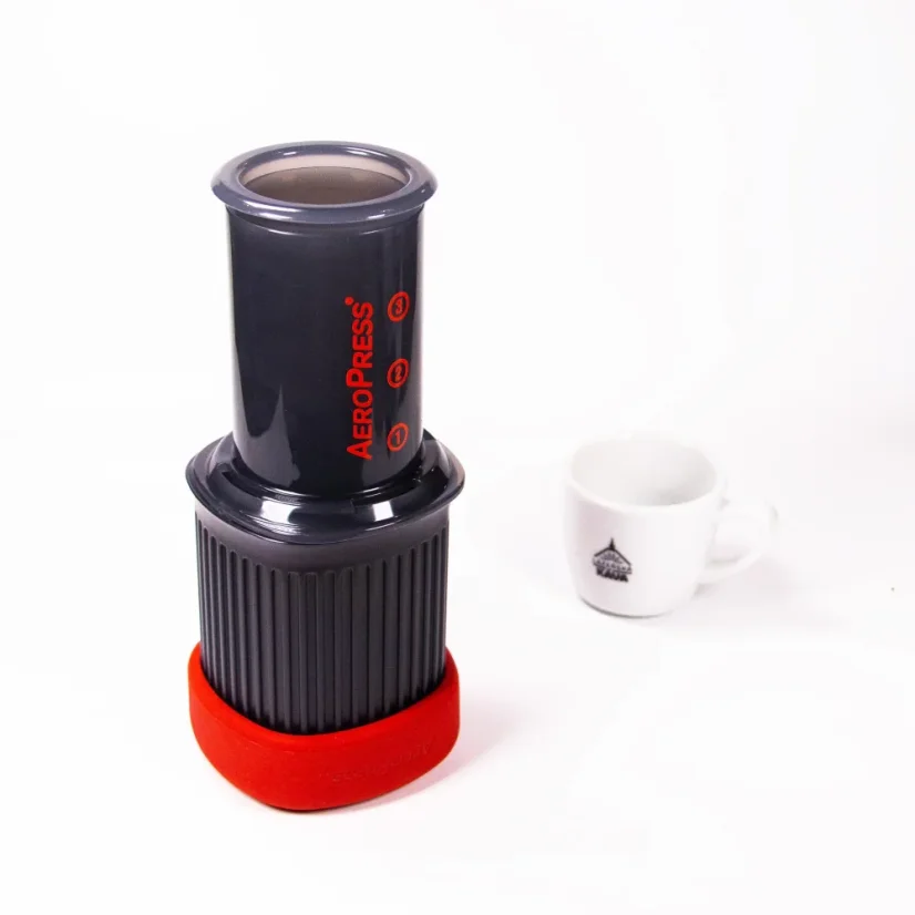 Aeropress on a white background with a cup of coffee