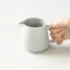 Serveuse de café grise tenue dans les mains.