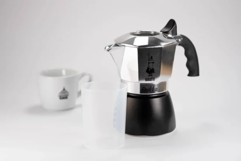 Cafetera Bialetti Brika para 2 tazas con una taza de café de fondo.